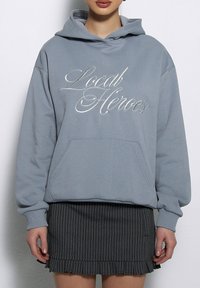 Błękitny, hoodies z kapturem z napisem "Local Heroes" wydrukowanym srebrnym pisma, z przednią kieszenią typu kangaroo i ściągaczami przy rękawach.