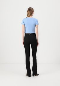 Light blue cropped t-shirt with short sleeves, paired with black fitted trousers featuring a subtle waistband tag, on a plain background.