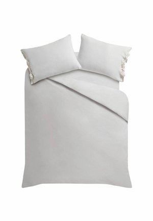 Weißes Bett mit zwei Kissen, die an den Seiten gebundene Schleifen haben, und einem teilweise gefalteten Bettbezug vor einem einfarbigen Hintergrund.