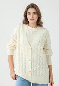 Cardigan in maglia cable-knit crema con grandi bottoni dorati, caratterizzato da texture con perline in rilievo, con scollo a V e vestibilità ampia.