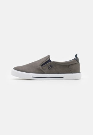 Γκρί δερμάτινο παπούτσι slip-on με λευκή ελαστική σόλα, ναυτικές λεπτομέρειες και χαμηλό προφίλ, διαθέτοντας ελαστικές πλευρές και στρογγυλή μύτη.