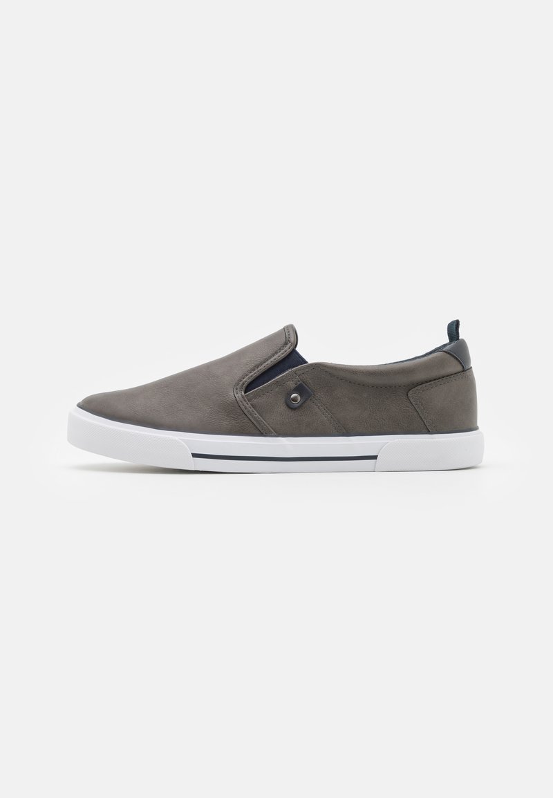 Chaussure en cuir gris à enfiler avec semelle en caoutchouc blanc, accents navy, et un design profil bas avec panneaux élastiques sur les côtés et bout rond.