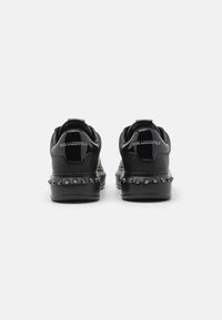 Sorte lædersneakers med en blank finish, der har en nitteret sål og præget branding på hælen. Moderne design med dristige accenter.