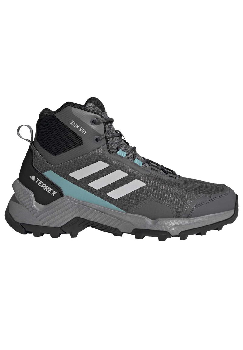 Szare buty trekkingowe z siateczkową i syntetyczną cholewką, z odblaskowymi białymi paskami, turkusowymi akcentami oraz wytrzymałą czarną podeszwą zapewniającą przyczepność.