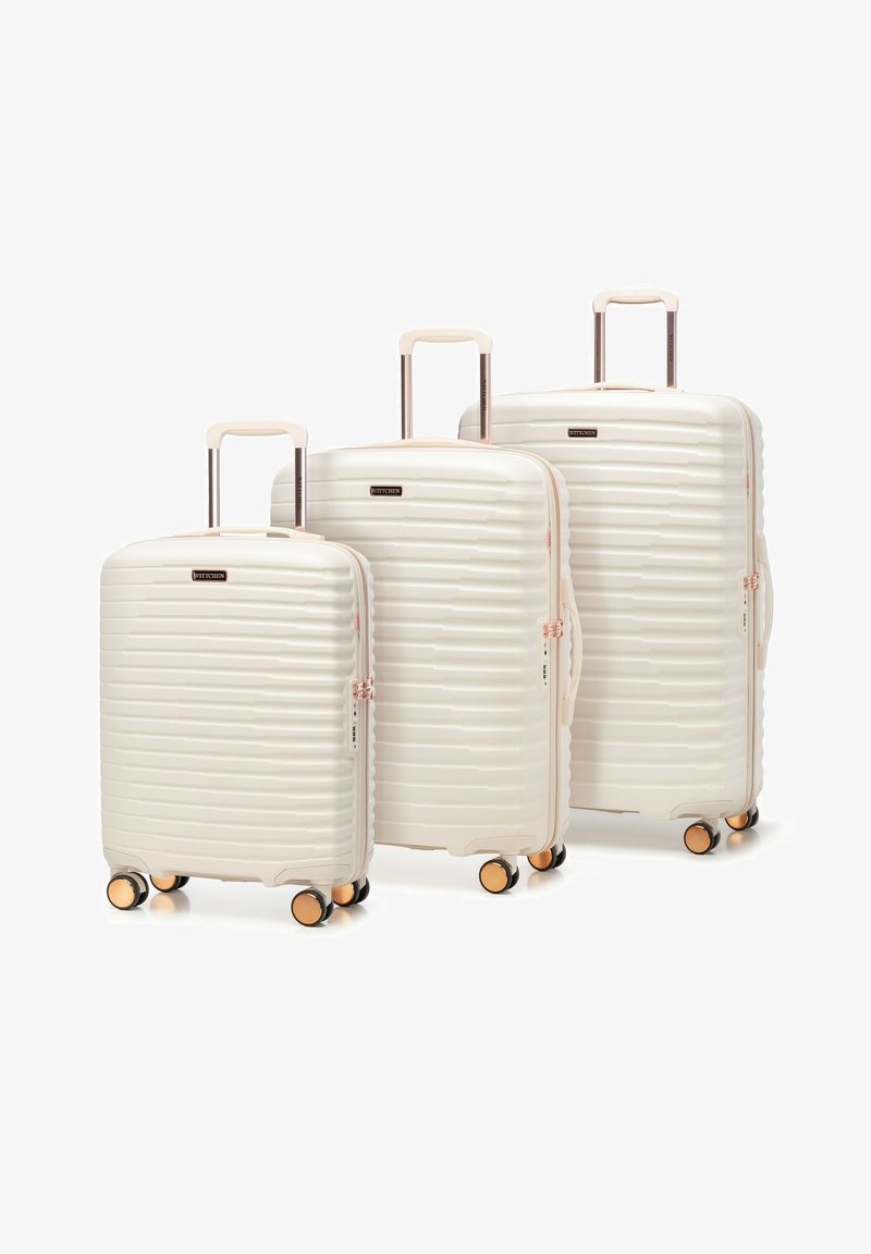 Three cream-colored hard-shell suitcases with four wheels and retractable handles, arranged from small to large, on a white background.