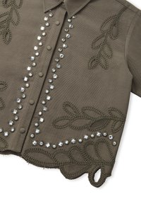 Vêtement vert olive avec un fermoir à boutons, orné de clous en argent et d'une broderie tressée complexe en motif de feuilles le long des bords.