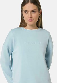 Lichtblauwe sweatshirt met een ronde hals, voorzien van een gestructureerde "CASUAL" opdruk op de voorkant en verlaagde schoudernaden. Glad stofgevoel.