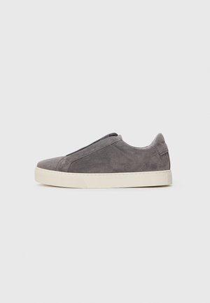 Sapatilha slip-on em camurça cinza com uma superfície texturizada, faixa elástica na parte da frente e sola de borracha branca. Design limpo e minimalista.