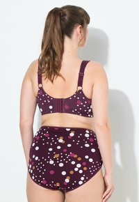 Bikini-Set mit maronenfarbenen Polka-Dots, featuring weißen und orangefarbenen Kreisen, mit verstellbaren Trägern und einem sicheren Häkchenverschluss am Rücken. Hoch geschnittene Bikinihose.