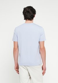 Ανοιχτό μπλε κοντομάνικο μπλουζάκι με στρογγυλή λαιμόκοψη, κατασκευασμένο από απαλό ύφασμα· διαθέτει απλό σχέδιο χωρίς ορατά μοτίβα ή διακοσμητικά στοιχεία.