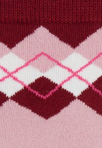 Knit sweater featuring an argyle pattern in dark red, pink, white, and light pink, with a textured ribbed collar.
