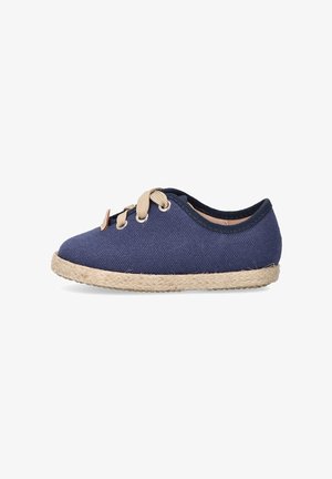 Zapatilla de lona azul marino con cordones beige, punta redonda y suela de yute trenzado. Textura suave con un diseño casual y ribete elástico en el tobillo.