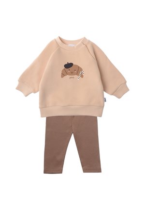 Beige Sweatshirt mit einem Croissant-Motiv und braunen, gerippten Leggings. Weicher Stoff, lockere Passform und gerippte Bündchen. Geeignet für die Freizeitkleidung.