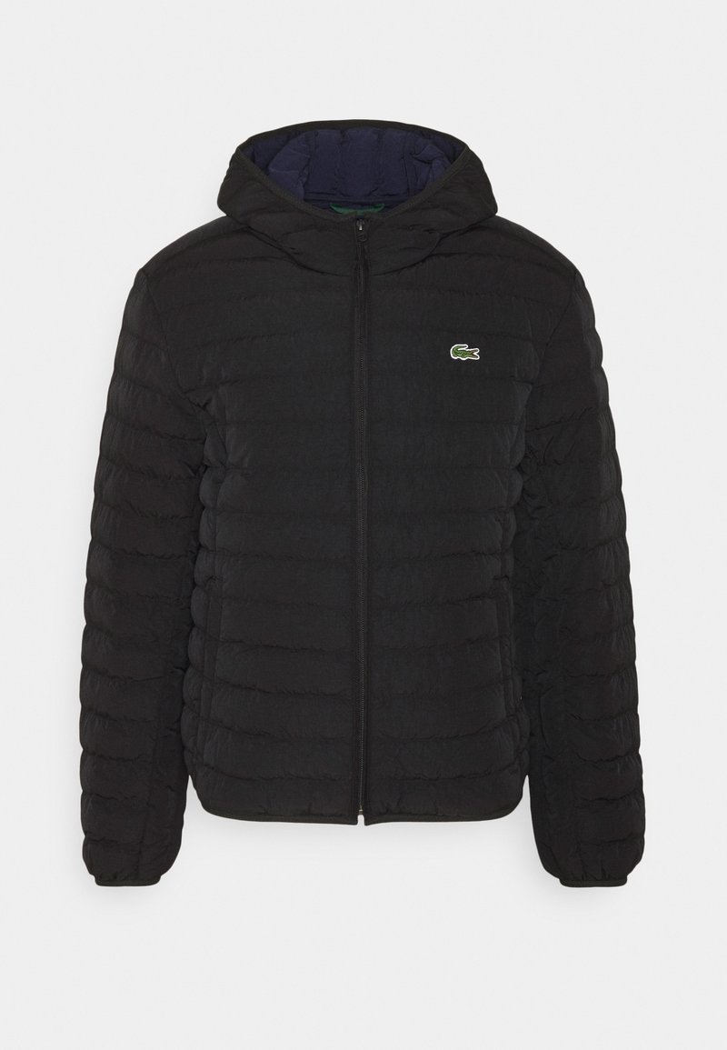 Schwarze Pufferjacke mit Kapuze. Merkmale sind die gesteppten Texturen und ein Reißverschluss auf der Vorderseite. Enthält ein kleines, grünes gesticktes Logo auf der linken Brust.