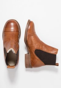 Brązowe skórzane botki za kostkę z elastycznymi panelami bocznymi, okrągłym noskiem i niskim, warstwowym obcasem. Posiadają miękkie wykończenie wewnętrzne i pętelkę do zakupu.