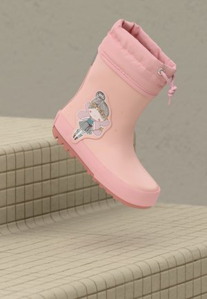 Botte de pluie rose pour enfants avec une illustration de fée et un système de fermeture à cordon, positionnée au-dessus de marches carrelées beiges.