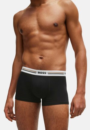 Schwarze Boxershorts aus glattem Material, mit einem weißen Bund, der schwarz-goldene Streifen aufweist, und dem Logo "BOSS" deutlich sichtbar.
