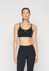 Musta urheilutoppi, jossa on ohuet hihnat, pyöreä pääntie ja näkyvä valkoinen Nike-logo edessä. Sujuva, joustava kangas ja istuva muotoilu.