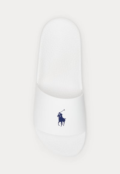 Hvite slidesandaler med teksturert fotseng og marineblå polo-spillerlogo på remmen, sett ovenfra.