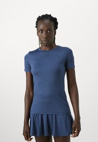 Activewear haljina u mornarsko plavoj boji s uskim gornjim dijelom i raširenom suknjom. Izrađena od rastezljivog materijala, s okruglim izrezom i kratkim rukavima.