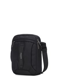 Borsa a tracolla in poliestere nero e texturizzato con tracolla regolabile, tasca con zip frontale e dettaglio del logo. Forma rettangolare compatta.