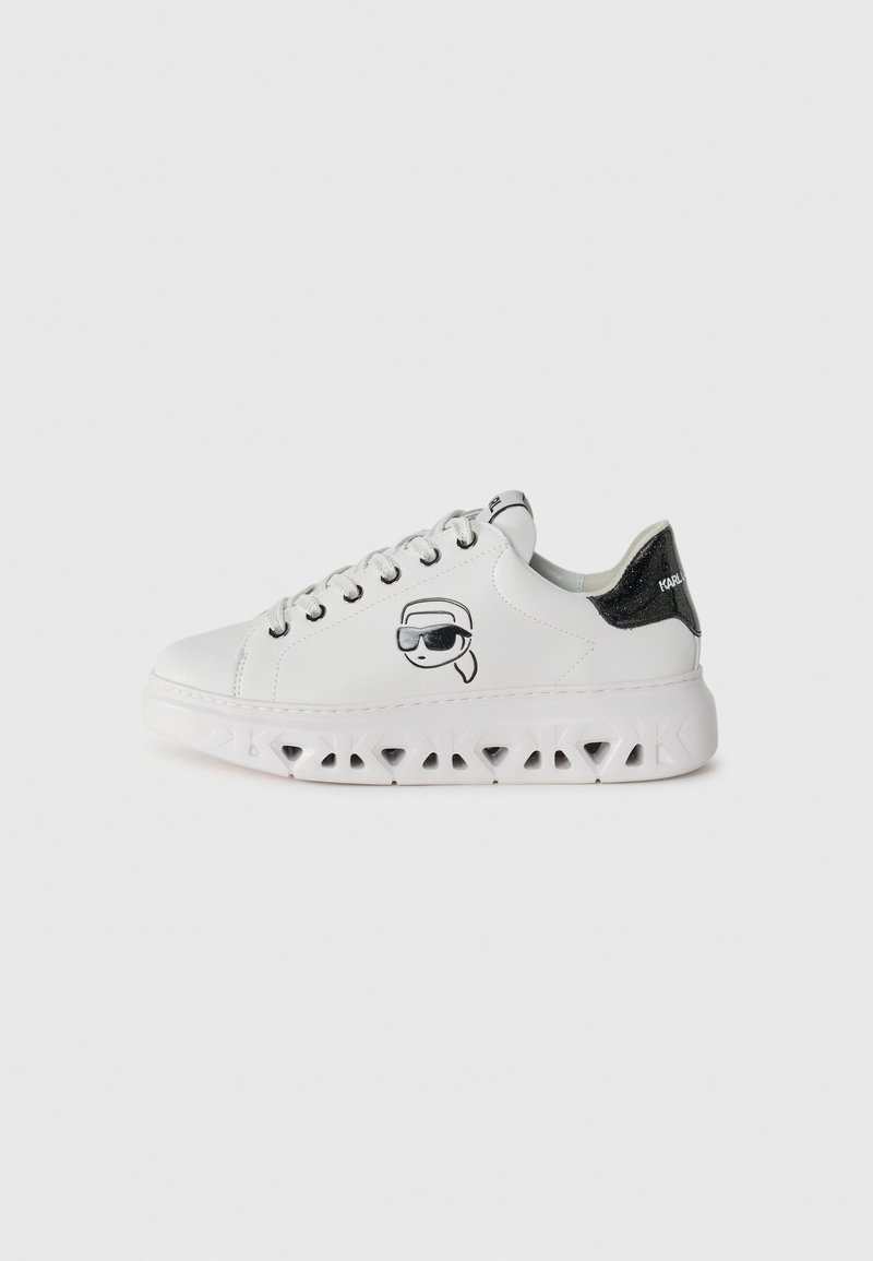 Sneaker bianchi con punta rotonda, suole bianche texturizzate, con un tacco a cappuccio nero glitterato e un personaggio stampato che indossa occhiali da sole.