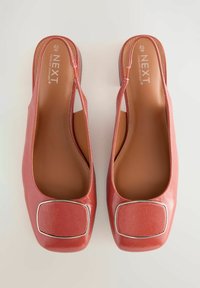 Punaiset synteettiset slingback-kengät, joissa on neliön muotoinen kärki, teksturoitu pinta ja metallinen neliökoriste edessä.