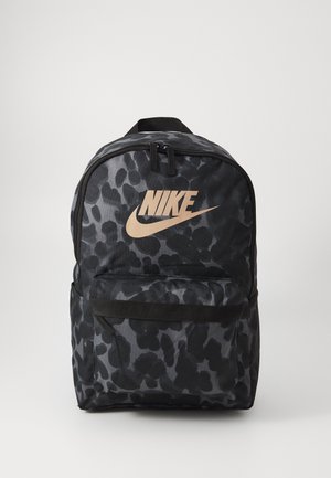 Sac à dos Nike à motif camouflage noir et gris avec poche avant zippée et logo beige sur fond uni.