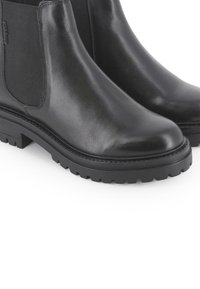 Botas Chelsea de cuero negro con paneles laterales elásticos, superficie texturizada, puntera redondeada y suelas de goma resistentes con patrones de relieve profundos.