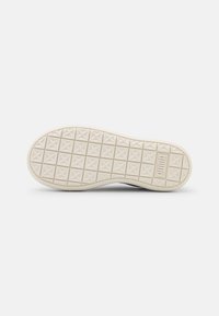 Semelle de chaussure avec une surface en caoutchouc texturé, présentant une grille de petites formes d'étoiles et une couleur blanc cassé. Marque discrète incluse.