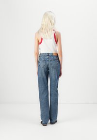Jeans din denim albastru cu talie înaltă, cu un design drept, având două buzunare la spate și o etichetă din piele maro pe talie.