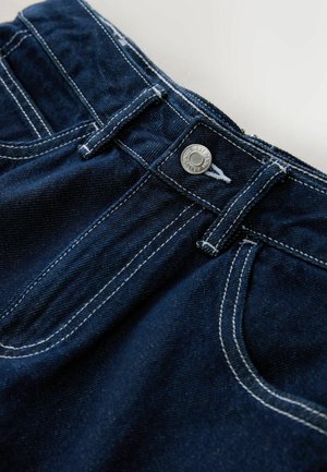 Dark blue denim trousers with white stitching, featuring a metal button closure and front pockets. Close-up view of the waistband.