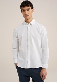 Witte lange mouwen knoopshirts van lichtgewicht stof, met een kraag en afgeronde zoom, gecombineerd met donkerblauwe broek.