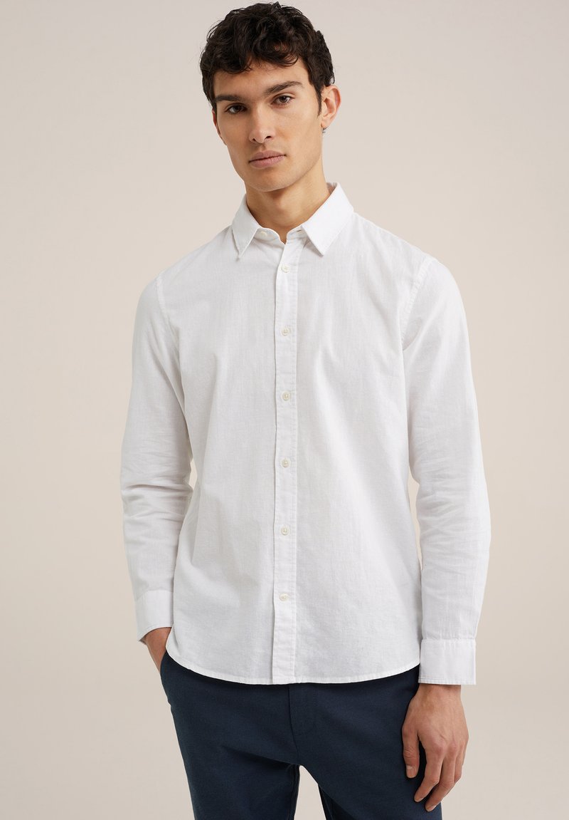 Witte lange mouwen knoopshirts van lichtgewicht stof, met een kraag en afgeronde zoom, gecombineerd met donkerblauwe broek.