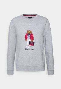 Felpa grigia con un personaggio di cane ricamato, indossante una giacca rossa, una maglietta a righe e pantaloni bianchi, con il testo "Hackett" sottostante.