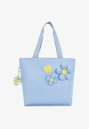 Borsa a mano azzurro chiaro con due fiori imbottiti blu e gialli e un distintivo logo circolare giallo, oltre a un piccolo portachiavi a righe.