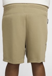 Knelånga shorts i kaki bomullsblandning, med en slät yta, elastisk midja och diskret sidficka med svart dragkedjedetalj.