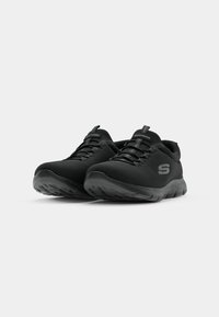 Black athletic shoes featuring a lightweight mesh upper, rounded toe, textured outsole, and lacing system with a logo on the side and tongue.