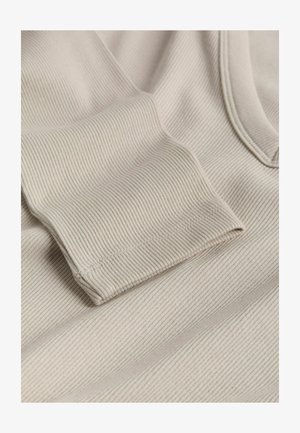 Béžová ribbovaná tkanina s texturovaným povrchem a ohrnutým rukávem. Materiál vykazuje jemné horizontální pruhy, což vytváří měkký a útulný vzhled.