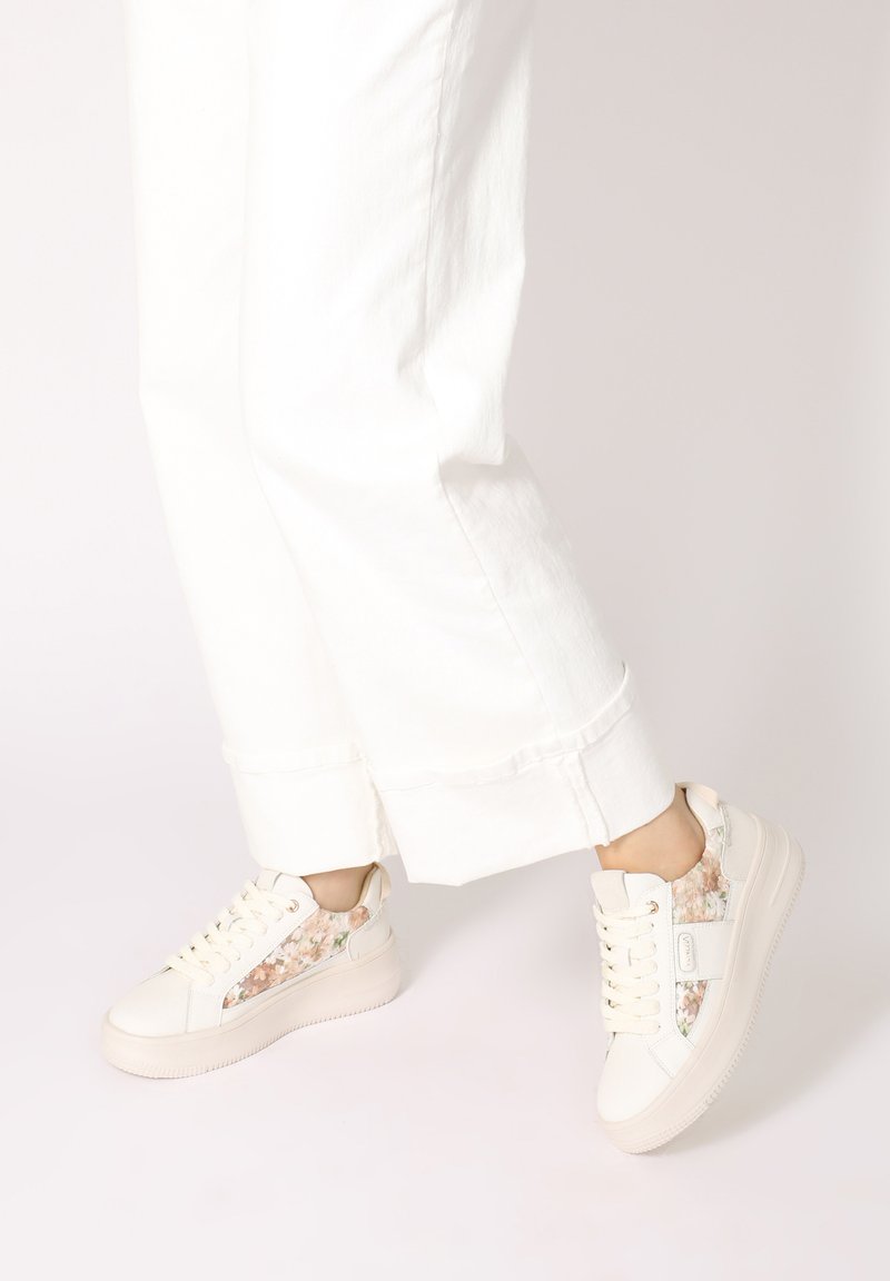 Weiße Sneakers mit floralen Stoffakzenten an den Seiten, strukturiertem Gummisohle und runder Zehenpartie. Die Schnürsenkel haben verstärkte Ösen für zusätzliche Haltbarkeit.