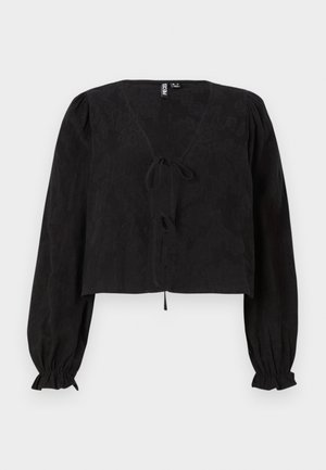 Blouse noire courte avec un décolleté en V, des manches bouffantes longues et un détail à nouer à l'avant. Le tissu texturé ajoute de la profondeur au design.