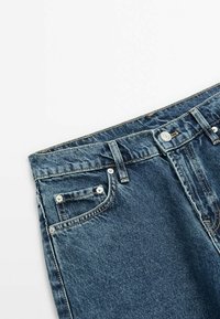 Jeans i denim med en mörkblå tvätt, utrustade med knapp och dragkedja, femfickorsdesign och subtila sömnadsdetaljer på midjan.