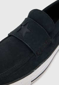Sorte semsket slip-on sko med stjerneaccent, med teksturert overdel, sømdetaljer og hvit gumm såle.