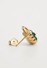 Guldfarvet ørepynt med et spiraldesign, der har grønne accenter og en klar sten. Inkluderer en synlig clasps i rustfrit stål med branding.
