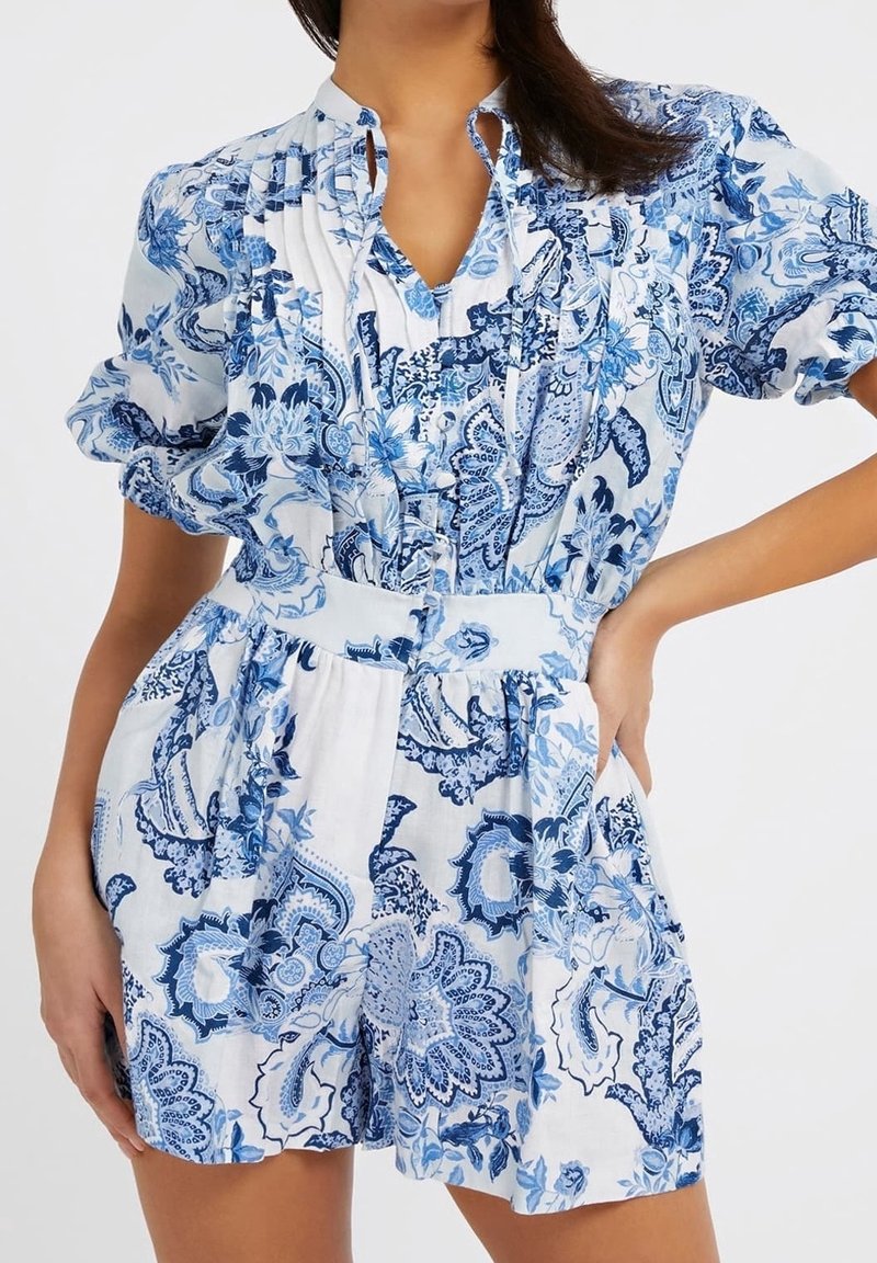 Vestido de manga corta con un patrón floral en azul y blanco, con un cierre de botones en la parte delantera, cintura fruncida y corte relajado. Fabricado en tejido ligero.