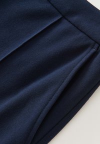 Tessuto blu navy con una texture liscia, caratterizzato da un design piegato e dettagli di cucitura delicati lungo l'orlo per dare struttura.