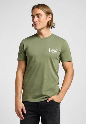 Olijfgroene t-shirt van zacht materiaal met korte mouwen, voorzien van een wit "Lee" logo aan de voorkant. Gecombineerd met donkerdenim jeans.