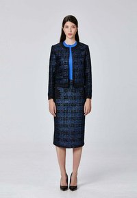 Un ensemble pour femmes composé de deux pièces, comprenant une veste texturée bleue et noire avec un col rond et une jupe crayon assortie. Le tissu a une finition éclatante.
