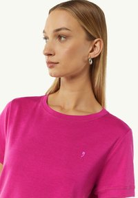 Rosa Baumwoll-T-Shirt mit rundem Ausschnitt, kurzen Ärmeln und einem kleinen gestickten Logo auf der linken Brust. Glatte Textur und lässige Passform.