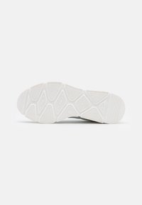 Semelle de basket blanche avec une surface texturée, présentant des motifs géométriques pour l'adhérence et la durabilité. Bords lisses et construction solide.